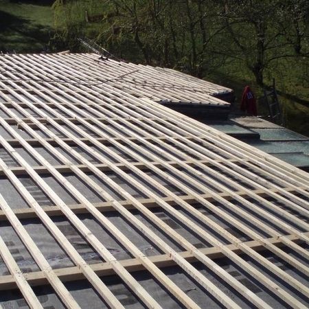 Auf einem flachen Dach liegt ein Holzgestell aus, vorbereitend für die Verkleidung