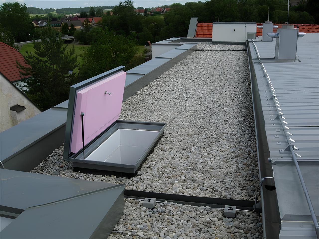 Flachdach, mit hellen Steinen ausgelegt und dunkler Umrandung sowie einem geöffneten Dachfenster